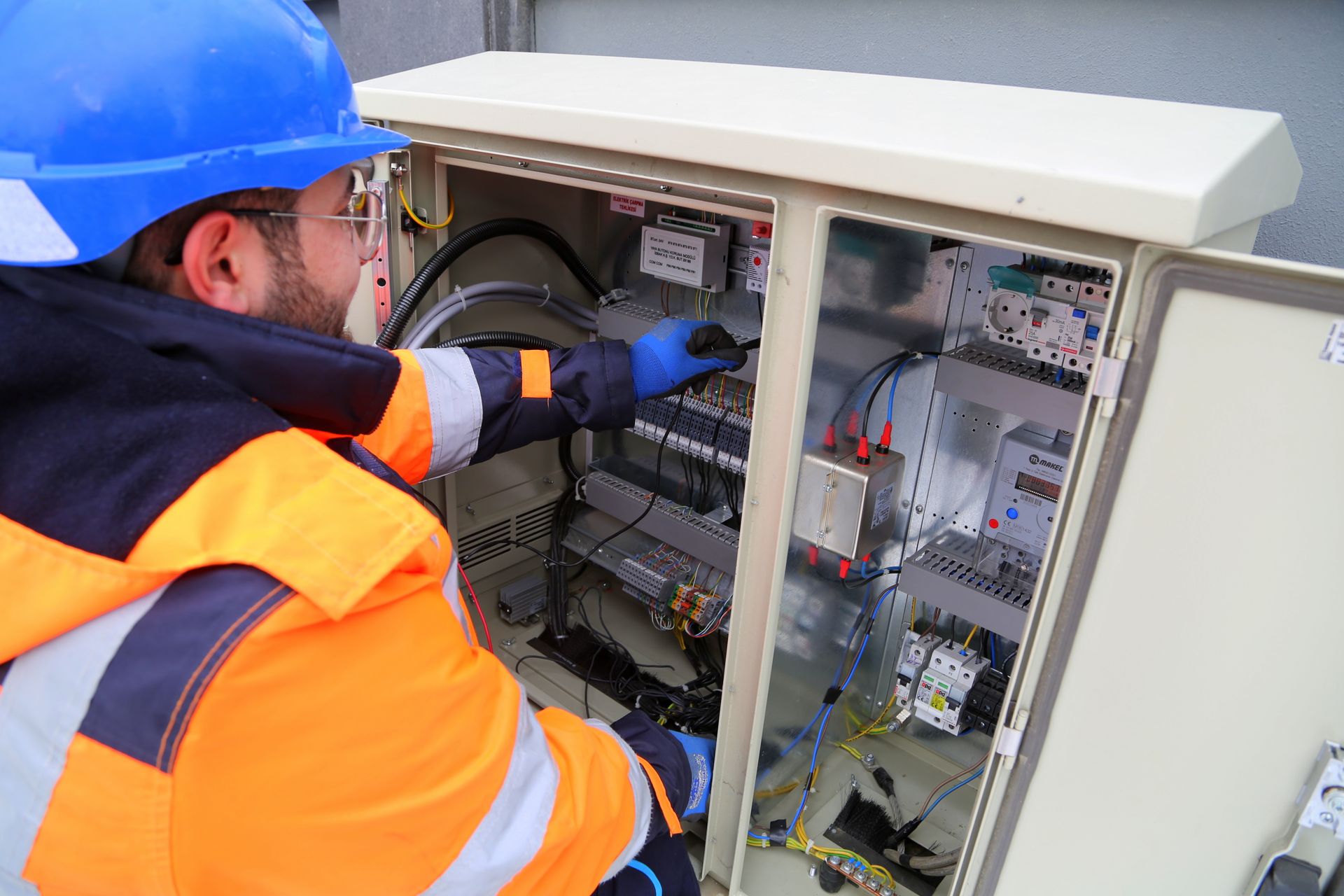 Električar u zaštitnoj opremi provjerava električni ormar