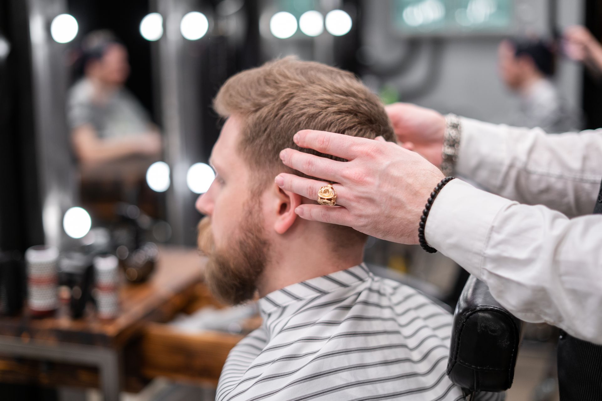 Barber češljem i škarama uređuje mušku frizuru